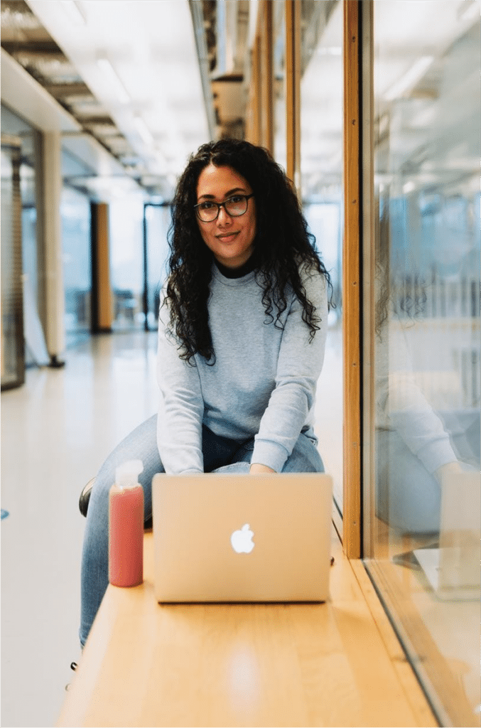 Vrouw zittend op bankje achter laptop